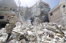 Civil defense members walk on rubble of a damaged site hit by what activists said was shelling on Tuesday by forces loyal to Syria's President Bashar al-Assad in Aleppo's al-Aryan neighborhood