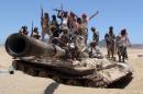 Anti-Houthi fighters of the Southern Popular Resistance stand on a tank in Yemen's southern port city of Aden