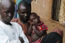 A man holds a boy as another looks on at the IDP camp for those fleeing violence from Boko Haram insurgents at Wurojuli