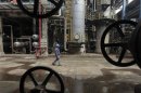 A worker walks past oil pipes at a refinery in Wuhan, Hubei province