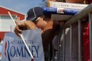 A supporter holds Republican presidential candidate and former Massachusetts Governor Romney's book "No Apology" and a copy of the "Book of Mormon" at a campaign rally in Commerce