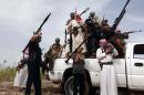 Armed Iraqi tribesmen on the back of a truck on a road north of Ramadi, on May 18, 2013