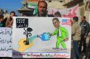 In this citizen journalism image provided by Edlib News Network, ENN, which has been authenticated based on its contents and other AP reporting, a protester holds a placard depicting U.S. President Barack Obama during a demonstration in Kafr Nabil town, Idlib province, northern Syria, Friday, Jan. 10, 2014. Rebel-on-rebel fighting between an al-Qaida-linked group and an array of more moderate and ultraconservative Islamists has killed nearly 500 people over the past week in northern Syria, an activist group said Friday, in the most serious bout of violence among opponents of Syrian President Bashar Assad since the civil war began. The Arabic on the poster is an acronym meaning, "the Islamic State of Iraq and the Levant." (AP Photo/Edlib News Network ENN)
