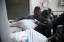 Men unload flour from a Red Crescent and United Nations aid convoy in the rebel held besieged town of Hamoria area in Syria