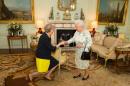 The new leader of the Conservative Party Theresa May (L) kneels as she is greeted by Britain's Queen Elizabeth II (R) at the start of an audience in Buckingham Palace in central London on July 13, 2016