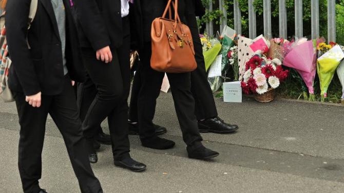 School pupils walk past floral tributes to slain teacher Ann Maguire outside Corpus Christi Catholic College in Leeds, on April 29, 2014