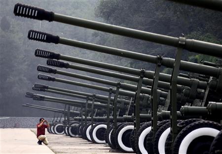 A visitor to the China Aviation Museum, located on the outskirts of Beijing, takes a photograph of a row of old anti-aircraft guns on display in this August 17, 2010 file photo. REUTERS/David Gray/Files