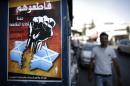A Palestinian man walks past a poster calling on people to boycott Israeli goods, on August 12, 2014, in the mostly Arab East Jerusalem