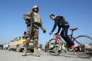 A boy cycles past Iraqi soldiers monitoring a checkpoint east of Baghdad on January 6, 2014