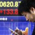 A man looks at his cellphone at an electronic stock board of a securities firm in Tokyo, Thursday, Jan. 24, 2013. Asian stock markets were mostly higher Thursday, supported by Congress averting a U.S. government default and a pickup in China's manufacturing in January.  (AP Photo/Koji Sasahara)
