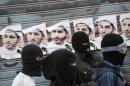 Bahraini protesters wearing masks look on during a confrontation with police after a demonstration against the arrest of Sheikh Ali Salman, head of the Shiite opposition movement Al-Wefaq
