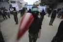 Masked member of Hamas movement carries a model of a rocket as others carry symbolic coffins with Israeli flags during a rally ahead of the 27th anniversary of Hamas founding, in the central Gaza Strip