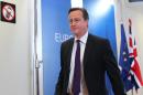 British Prime Minister David Cameron walks past a sign prohibiting the use of mobile phones, after he addressed the media at the European Council building in Brussels, Friday, Oct. 25, 2013. Migration, as well as an upcoming Eastern Partnership summit, tops the agenda in Friday's meeting of EU leaders. (AP Photo/Yves Logghe)