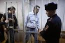 Russian opposition activist and anti-corruption crusader Alexei Navalny, 38, second right, and his brother Oleg Navalny, left, enter into the cage at a court in Moscow, Russia, Tuesday, Dec. 30, 2014. Alexei Navalny, the anti-corruption campaigner who is a leading foe of Russian President Vladimir Putin, has been found guilty of fraud and given a suspended sentence of three and a half years. (AP Photo/Pavel Golovkin)