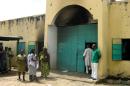 Prison staff members stand outside a partly scorched exterior of the central prison in the northern Nigerian city of Bauchi on September 8, 2010