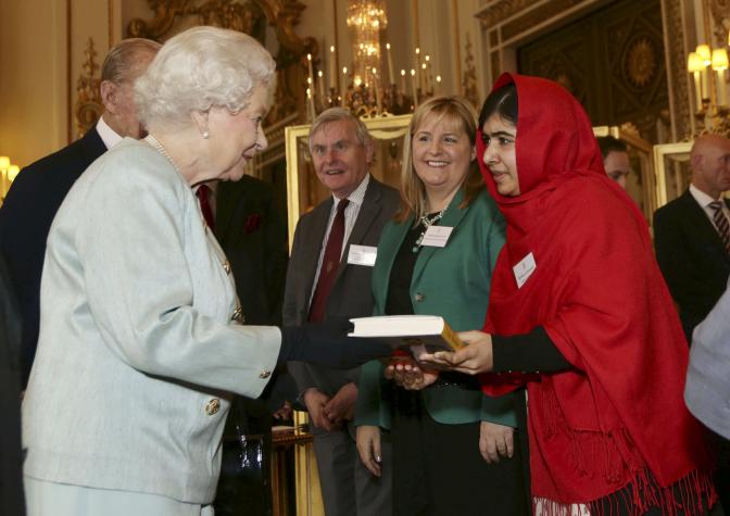 Malala Yousafzai gives a copy of her book to Britain's Queen Elizabeth during a Reception at Buckingham Palace in London