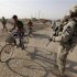 A resident rides a bicycle past U.S. Army soldiers on the outskirts of Kut