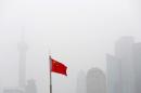 Chinese flag is seen in front of the financial district of Pudong amid heavy smog in Shanghai