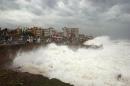 Indian people watch high tide waves as they stand at the Bay of Bengal coast in Vishakhapatnam, India, Saturday, Oct. 12, 2013. Hundreds of thousands of people living along India's eastern coastline were taking shelter Saturday from a massive, powerful cyclone Phailin that was set to reach land packing destructive winds and heavy rains. (AP Photo)