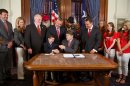 After signing a law protecting Christmas and other holiday celebrations inTexas public schools from legal challenges Texas Governor Rick Perry, center hands the pen to Reagan Bohac, 8, son of the bill's sponsor, Houston Republican Rep. Dwayne Bohac, fifth from left, Thursday, June 13, 2013, in Austin, Texas. (AP Photo/Texas Legislature, Stephen Stephanian)