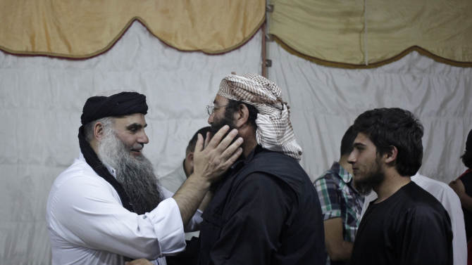 In this Wednesday, Sept. 24, 2014 photo, radical al-Qaida-linked preacher Abu Qatada, first left, receives a friend, on the day he was released from Jordanian prison after an acquittal on security charges, in Amman, Jordan. Abu Qatada and Abu Mohammed al-Maqdisi, two of Jordan's top pro-al-Qaida ideologues held court on the rooftop of a villa whispering to each other and rising occasionally from plastic chairs to greet supporters. The two have denounced some of the Islamic State group's practices as un-Islamic - comments some analysts say have turned the preachers into assets in Jordan's campaign to contain the Islamic State, which is believed to have attracted thousands of followers in Jordan. (AP photo/Mohammad Hannon)