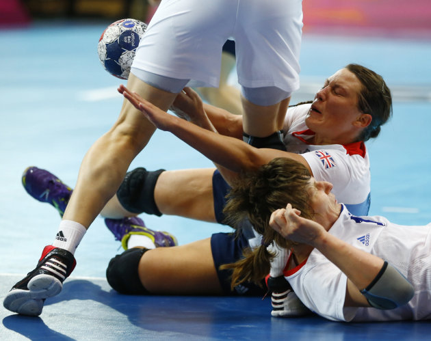 Britain&#39;s Ewa Palies tries to hold on to the ball after colliding with Russia&#39;s Nadezda Muravyeva and Natalia Shipilova in their women&#39;s handball Preliminaries Group A match at the Copper 