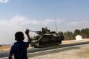 A Turkish boy waves to Turkish tank convoy driving into Syria from the border city of Karkamis in the southern region of Gaziantep, on August 26, 2016