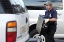 An investigator carries out a computer hard drive from the apartment of the suspect who opened fire in a movie theater in Aurora
