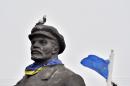 A pigeon sits on a Soviet era statue of Lenin with a Urkainain flag wrapped around it as an EU flag flies in the background, near the the eastern Ukrainian city of Slavyansk, in Donetsk region, on March 12, 2015