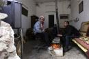 Free Syrian Army fighters warm themselves around a heater inside a room in Deir al-Zor
