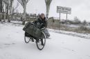 Local woman pushes her bicycle near a sign to the town of Vuhlehirsk, west of Debaltseve