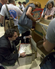 Eli Zimmerman, lower left, who says he has "a record addiction," kneels as he browses his selections at the New York City Public Library for the Performing Arts at Lincoln Center, Friday, Aug. 9, 2013. The library is selling 22,000 duplicate vinyl records that were preserved in mint condition to raise money for the expansion of the library. (AP Photo/Richard Drew)