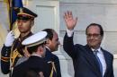 French President Francois Hollande (R) waves next to Egyptian counterpart Abdelfattah al-Sisi (C) after reviewing the honour guard during a welcome ceremony at the al-Quba presidential palace in Cairo on April 17, 2016