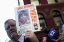 NYPD spokesman Paul Brown holds an original missing poster of Etan Patz during a news conference near a New York City apartment building, where police and FBI agents were searching a basement for clues in the boy's 1979 disappearance, in New York