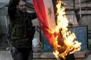 A rebel fighter burns a Syrian flag found in a building that belonged to Syrian government forces in the northern city of Aleppo on November 21, 2013