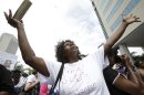Maeguerita Quire, of Miramar, Fla., holds up a Bible as she sings along during a "Justice for Trayvon" rally, Saturday, July 20, 2013 in Miami. The Rev. Al Sharpton's National Action Network organized "Justice for Trayvon" rallies nationwide to press for federal civil rights charges against George Zimmerman, who was found not guilty in the shooting death of unarmed teenager Trayvon Martin. (AP Photo/Wilfredo Lee)