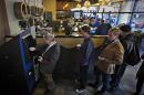 Customers line-up to use the world's first ever permanent bitcoin ATM unveiled at a coffee shop in Vancouver