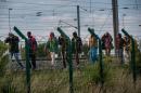 Migrants who successfully crossed the Eurotunnel terminal walk on the side of the railroad as they try to reach a shuttle to Great Britain, on July 28, 2015 in Frethun, northern France