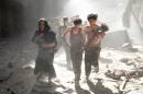 A Syrian woman and youths flee the site of a reported barrel-bomb attack by government forces in the northern city of Aleppo on June 26, 2014