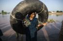 A Pakistani woman carries a rubber ring as she stands beside a flooded field following heavy rain in Cheniot