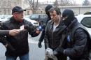Lehel, alleged hacker "Guccifer", is escorted by masked policemen in Bucharest, after being arrested in Arad