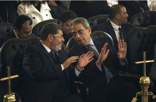 FILE - In this Friday, Jan. 6, 2012 file photo, Mohamed Morsi, left, of Egypt's Muslim Brotherhood and Egyptian presidential hopeful Amr Moussa, right, talk before Christmas Eve mass, led by Coptic Pope Shenouda III at the Coptic cathedral in Cairo, Egypt. In the race to become the first president of the new Egypt, the secular candidate with the strongest chance of beating increasingly powerful Islamists has to overcome the baggage he brings from the old Egypt. On the campaign trail ahead of next month's landmark vote, the 76-year-old Amr Moussa presents himself as an elder statesman with years of experience in politics and government, first from a decade as foreign minister under former President Hosni Mubarak, then from another decade leading the Arab League. (AP Photo/Maya Alleruzzo, File)