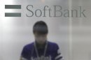 A shop clerk is seen through a window displaying a logo of SoftBank Corp at its branch in Tokyo June 21, 2013.