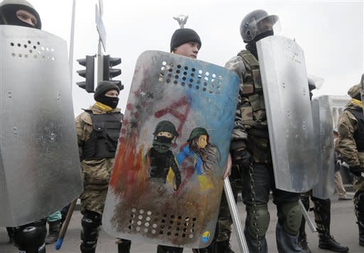 متظاهر في أوكرانيا يحمل درعا للحماية من الشرطة وقد رسم على درعه صورته مع حبيبته