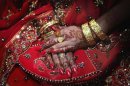 A Pakistani bride folds her hands decorated with henna and jewellery at her wedding party