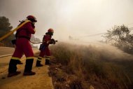 Dos bomberos combaten el incendio forestal de la provincia de Valencia, iniciado en el término municipal de Cortes de Pallás, este sábado cerca de la localidad de Turis