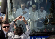 A man makes a heart shaped sign to Turkish Prime Minister Recep Tayyip Erdogan and his wife Emine to show support after his arrival in Ankara, Turkey, Sunday, June 9, 2013. (AP Photo/Vadim Ghirda)