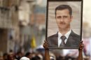A Shi'ite anti-government protester holds up a poster of Syrian President Bashar al-Assad during a demonstration against Israeli air strikes in Syria, in Sanaa