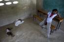 Milene Monime, 16, sits as her two-month-old son Jefferson Thezon, center, sleeps next to another person's child inside a school classroom where her family and others are staying after being deported the previous day from neighboring Dominican Republic, in the village of Fonbaya, Haiti, Thursday, June 18, 2015. People began preparing Thursday for deportation from the Dominican Republic after failing to obtain legal residency as part of a government program to crack down on migrants, most of them from neighboring Haiti or of Haitian descent. (AP Photo/Rebecca Blackwell)