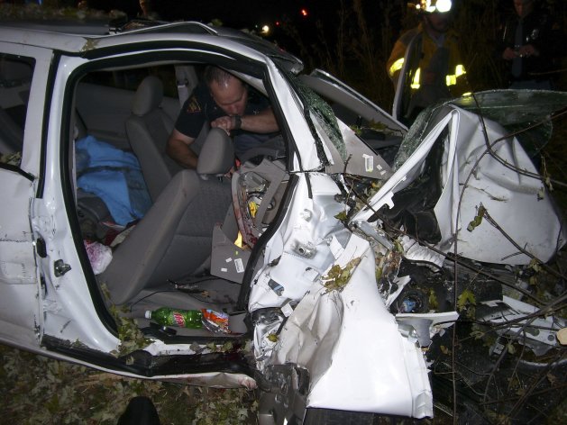 A Wisconsin State Patrol police officer looks through the wreck of a 2005 Chevy Cobalt in St Croix County, Wisconsin in this October 24, 2006 file photo. Megan Phillips, who was the driver of a 2005 Chevrolet Cobalt that crashed in Wisconsin, said that until last month's recall she blamed herself for a 2006 accident in which two teenaged friends were killed when her car left the road and hit a clump of trees. REUTERS/St Croix Sherriff/Handout (UNITED STATES - Tags: TRANSPORT CRIME LAW BUSINESS POLITICS) ATTENTION EDITORS - THIS IMAGE HAS BEEN SUPPLIED BY A THIRD PARTY. IT IS DISTRIBUTED, EXACTLY AS RECEIVED BY REUTERS, AS A SERVICE TO CLIENTS. FOR EDITORIAL USE ONLY. NOT FOR SALE FOR MARKETING OR ADVERTISING CAMPAIGNS